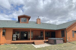 A wooden house with a covered porch, a hot tub, and a grill.
