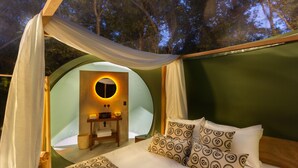 Een gezellige, ronde slaapkamer in tentstijl, met een bed, kussens en een kaptafel met spiegel.
