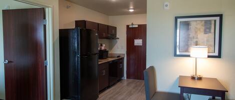 A compact kitchen with dark wooden cabinets, a black refrigerator, and a small dining area with a table and chairs.