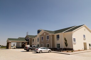 A hotel with a covered parking area, multiple buildings, and a clear sky.