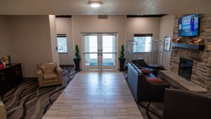 A spacious living area with a fireplace, comfortable seating, and a large window. - Cobblestone Inn & Suites - Springfield (Springfield)