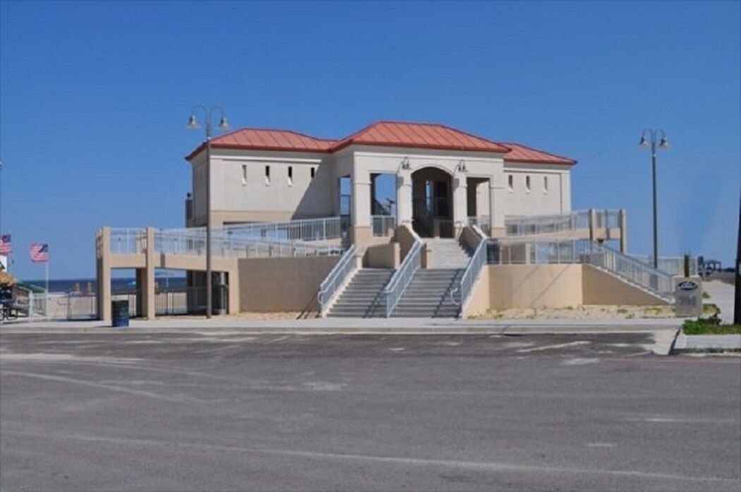 Un bâtiment avec un toit rouge, un escalier menant à l’entrée et un ciel bleu clair en arrière-plan.