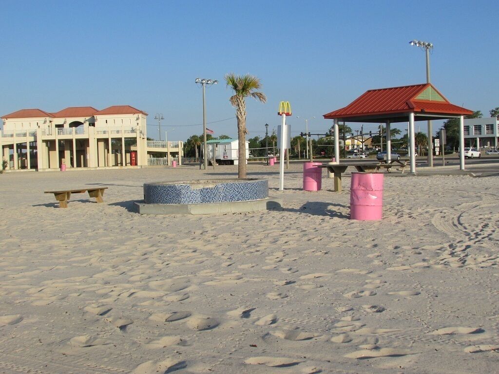 Une plage avec un bâtiment, un palmier et une enseigne McDonald's.