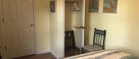 Une chambre à coucher avec un lit, une chaise, une porte et un placard.