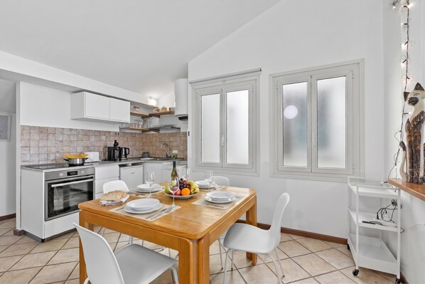 A modern kitchen with white cabinets, a wooden dining table, and a kitchen island. - Rooftop - AC, Lake View with Terrace, Stresa, Italy (Stresa)