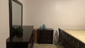 A bedroom with a bed, a dresser, a mirror, and a small table with a vase. - Five minutes (Lauderhill)