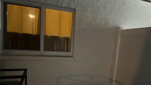 A room with a window, a white wall, and a corner with a concrete block. - Five minutes (Lauderhill)