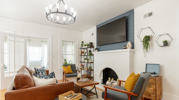 Una sala de estar con chimenea, un televisor montado encima y una estantería.