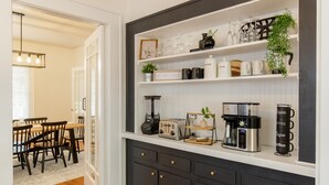 Una cocina con estación de café, que incluye cafetera, molinillo y tazas.