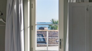Une vue à travers une porte dotée d’une fenêtre, révélant un bâtiment avec un toit en pente et une plante à l’extérieur.