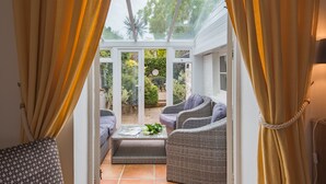 A conservatory with wicker furniture and a glass door leading to a garden. - Charming holiday  cottage in the centre of Deal, sleeping 6 guests, 2 bathrooms seconds from the sea (Deal)