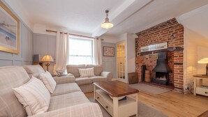A cozy living room with a sofa set, a wooden coffee table, and a brick fireplace. - Charming holiday  cottage in the centre of Deal, sleeping 6 guests, 2 bathrooms seconds from the sea (Deal)