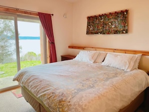 Un dormitorio con una cama grande, cabecera de madera, una mesita de noche y un cuadro en la pared.