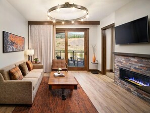 Relax in this stylish living room with a comfortable sofa, flat-screen TV, and fireplace, offering a view of the outdoors through a large window.