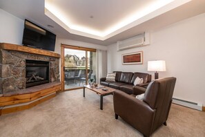 A living room with a stone fireplace, leather sofa, and a flat-screen TV.