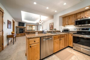 Una cucina moderna con ripiani in granito, elettrodomestici in acciaio inossidabile, mobili in legno e lavastoviglie integrata.