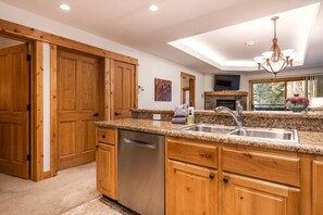 A kitchen with wooden cabinets, granite countertops, a dishwasher, and a skylight.