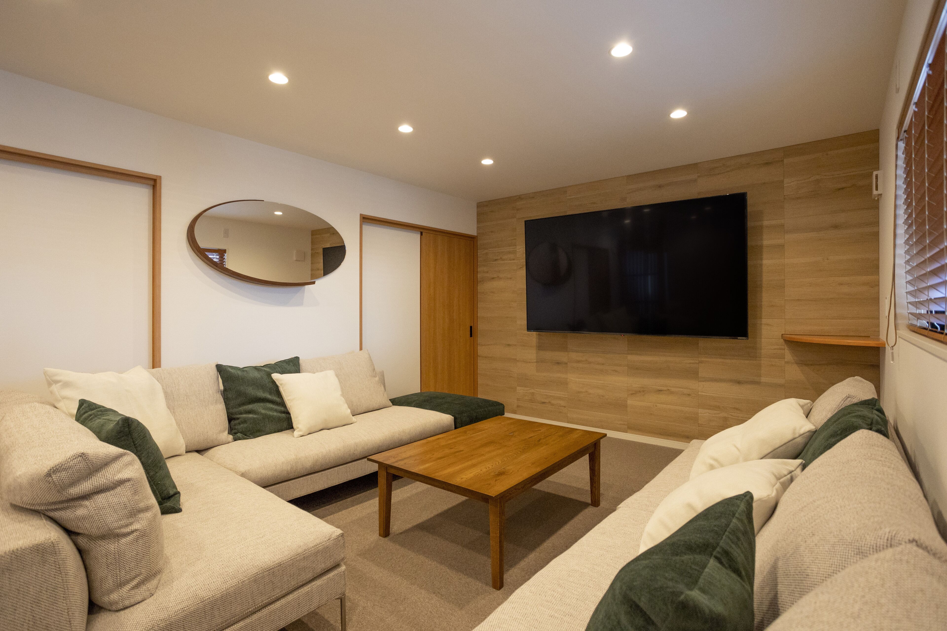 A modern living room with a sofa, coffee table, and a flat-screen TV mounted on the wall.