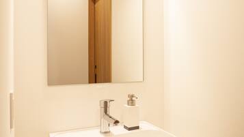A bathroom with a white sink, a mirror, and a wooden tray.