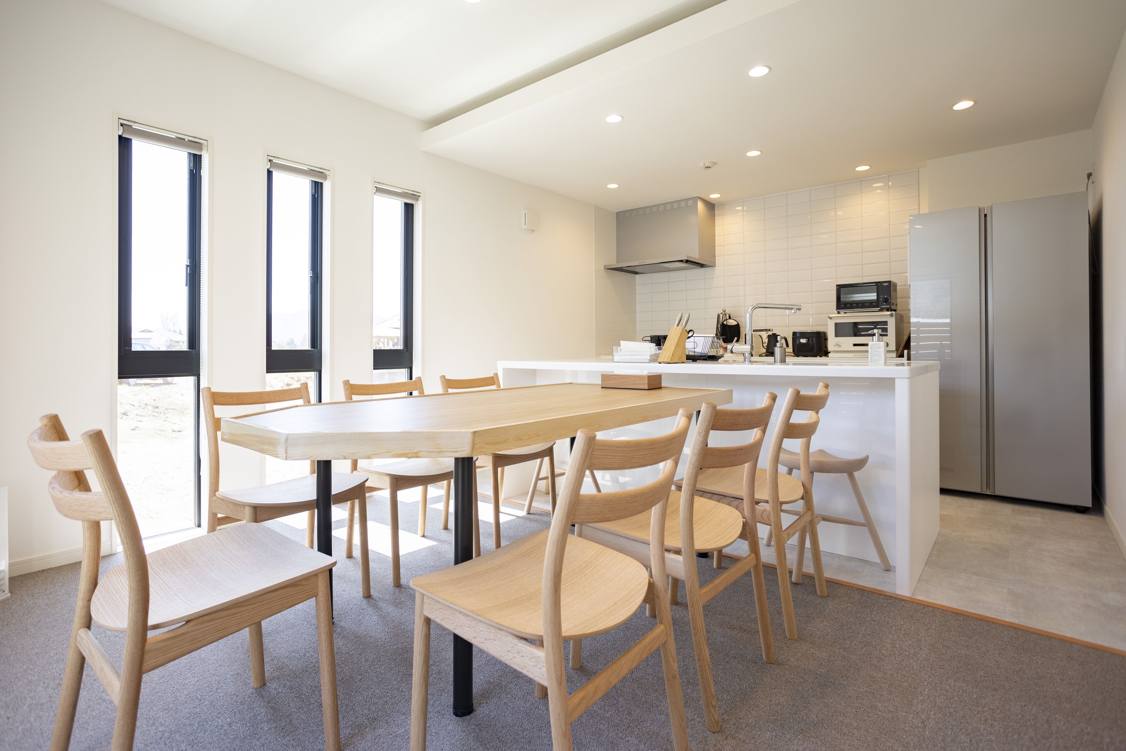 A modern kitchen with a central island, white cabinetry, and stainless steel appliances.