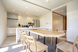 Una cocina moderna con armarios blancos, una isla central y sillas de madera.