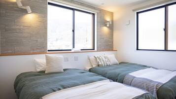 A modern bedroom with two beds, large windows, and built-in lighting.
