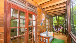 Une cabane en bois avec un hamac, un canapé et une grande fenêtre.