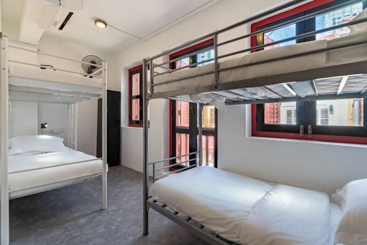 A bunk bed room with a window, a bed, and a headboard.