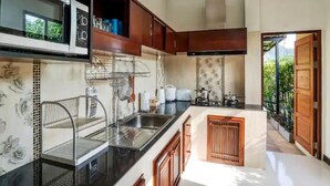 A modern kitchen with a microwave, sink, and wooden cabinets.