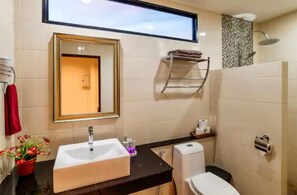 Un baño moderno con un espejo grande, un lavamanos, un inodoro y una ducha.