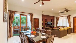 A dining area with a table set for four, a sofa, and a ceiling fan.