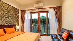A hotel room with a bed, a sofa, a patterned wall, and a sliding glass door to the outside.