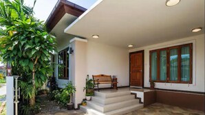 A modern house with a white exterior, a wooden door, and a bench outside.