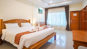 A hotel room with a large bed, a wooden headboard, a desk, and a chair. - Prayai Changthai Resort (Chalong)