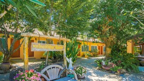 A courtyard with a wooden bench, potted plants, and a sign for Prayaichang Thai Resort. - Prayai Changthai Resort (Chalong)