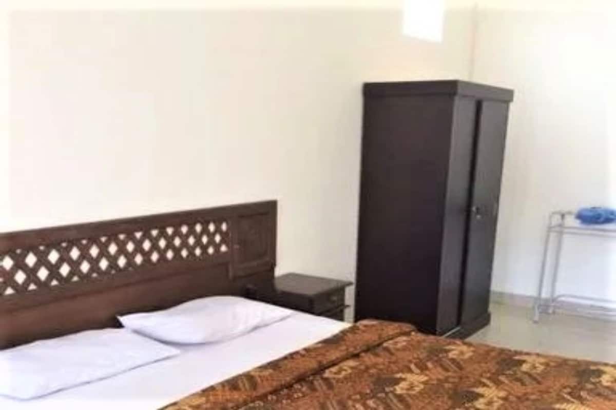 Une chambre à coucher avec un lit, une armoire et une petite table avec une lampe.
