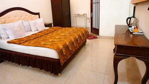Une chambre à coucher bien rangée, avec un grand lit, une armoire en bois, un bureau avec une lampe et un radiateur.