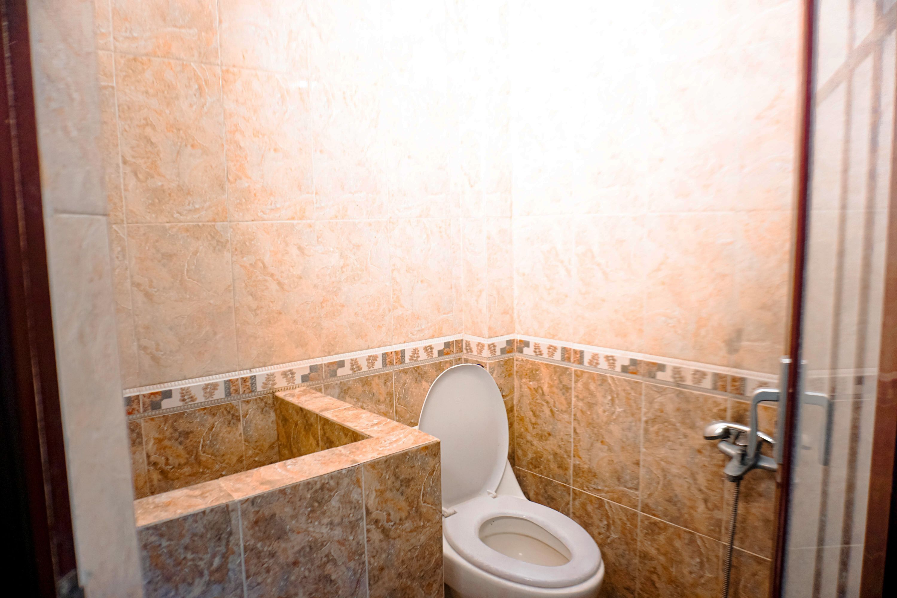 A bathroom with a toilet, shower, and tiled walls.
