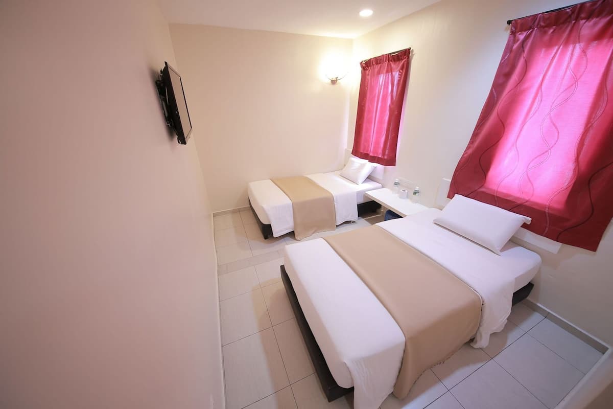 A hotel room with two beds, a desk, a mirror, and a wall-mounted TV.