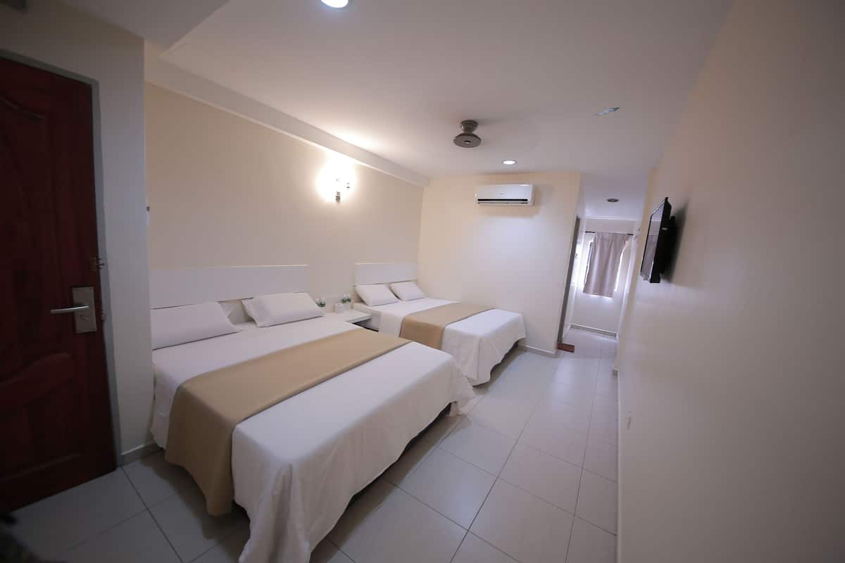 A hotel room with two beds, a ceiling fan, an air conditioning unit, and a television on the wall.