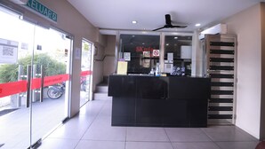 A reception area with a black counter, glass doors, and a ceiling fan. - Skudai Hotel Universiti Teknologi Malaysia (Johor Bahru)
