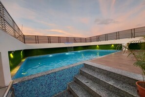 Ein Schwimmbecken mit einer gefliesten Kante, einer Treppe, die zum Wasser führt, und einem Geländer darüber.