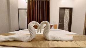 A hotel room with a neatly made bed, a brown curtain, and a door with a decorative panel.