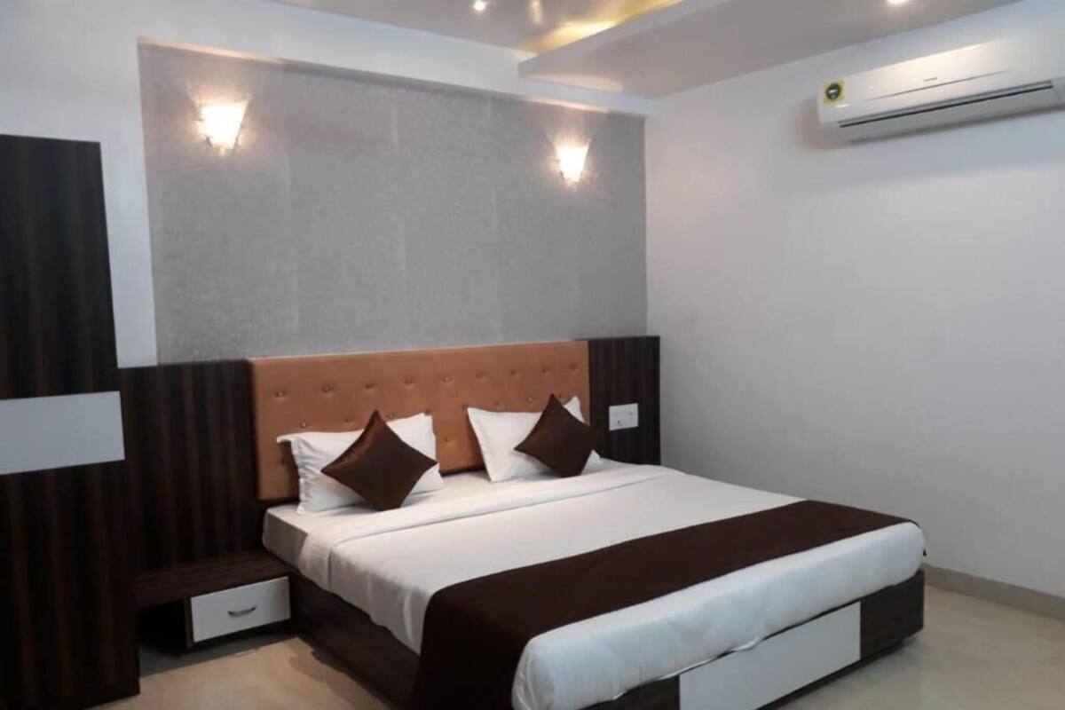 Une chambre d’hôtel moderne avec un grand lit, une table de chevet, un petit tiroir et un appareil de climatisation.
