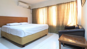 Une chambre d’hôtel avec un lit, un canapé, une petite table et une fenêtre avec des rideaux.