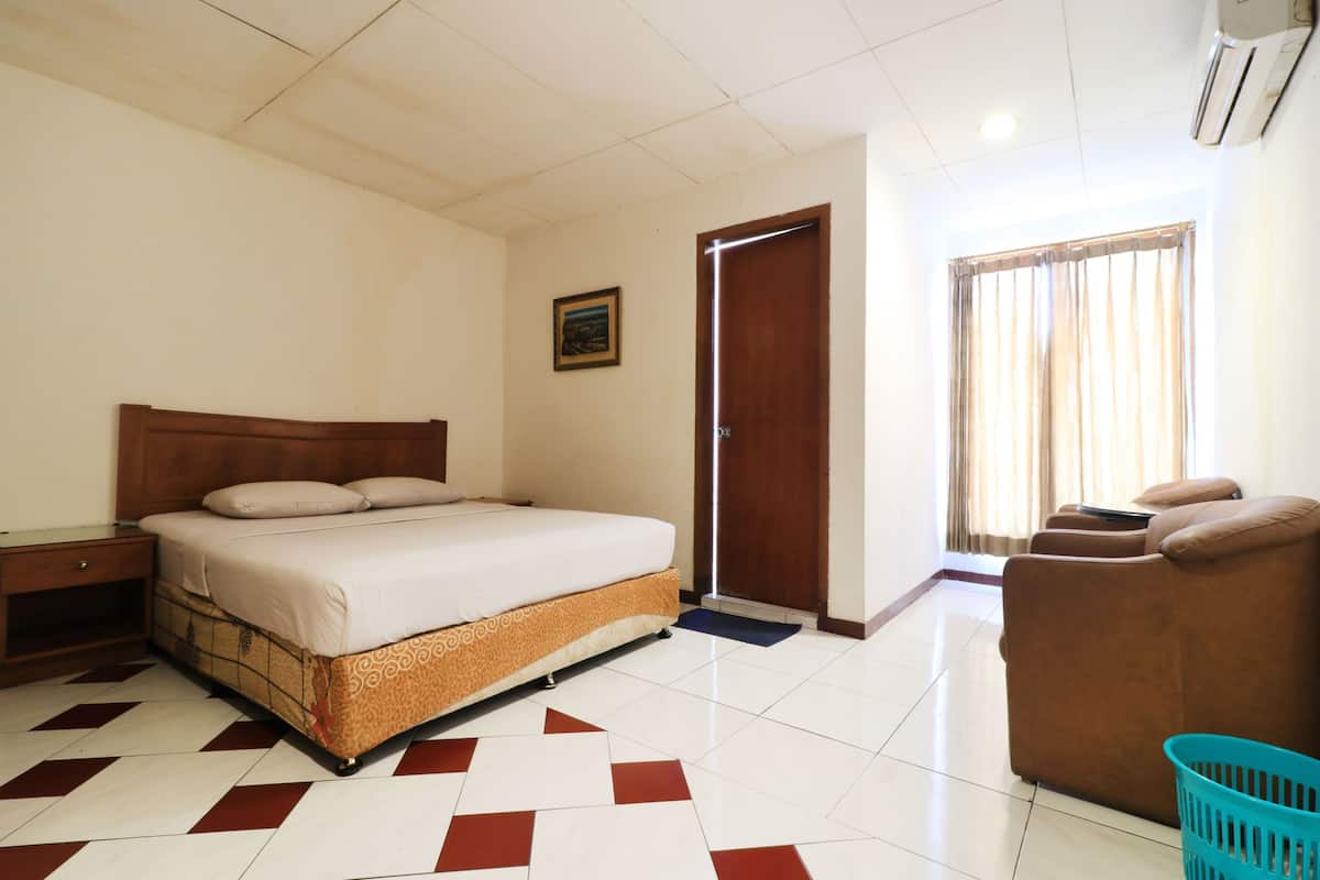 Une chambre d’hôtel comprenant un lit, une table de chevet, un canapé, une fenêtre avec des rideaux et un climatiseur fixé au mur.