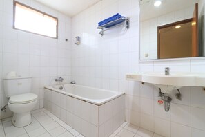 A bathroom with a toilet, bathtub, sink, and a towel rack. - Mroom Prapancha  (Jakarta)