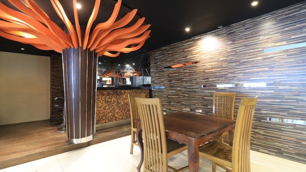 Un espace de salle à manger moderne avec une table et des chaises en bois, un luminaire décoratif de couleur orange et un mur à texture.