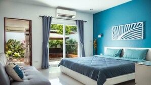 Un dormitorio moderno con cama, sofá y vistas al exterior.