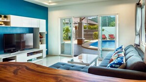 Una sala de estar moderna con un televisor de pantalla plana, una mesa de centro de madera y un sofá gris con cojines estampados.